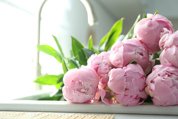 Bouquet of beautiful pink peonies in kitchen sink