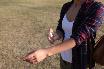 Woman applying insect repellent onto arm outdoors, closeup