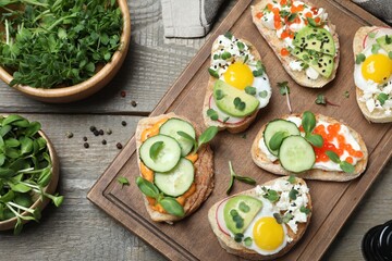 Different delicious sandwiches with microgreens on wooden table, flat lay