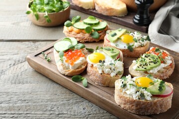 Different delicious sandwiches with microgreens on wooden table