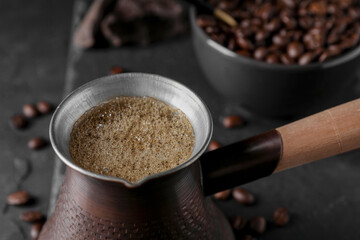 Cezve with Turkish coffee on dark grey table, closeup