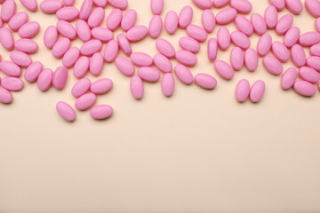 Many pink dragee candies on yellow background, flat lay. Space for text