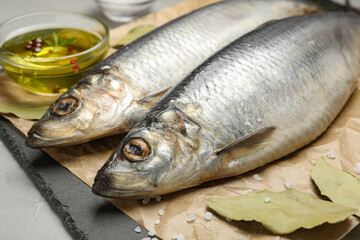 Slate plate with salted herrings, oil and spices on grey table, closeup