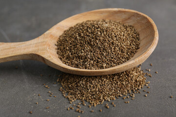 Spoon of celery seeds on grey table, closeup