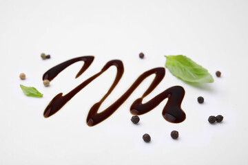 Organic balsamic vinegar, peppercorns and basil leaves on white background