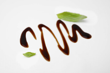 Organic balsamic vinegar and basil leaves on white background
