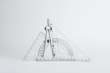 Triangle ruler, protractor and compass on white background