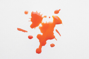 Blot of orange ink on white background, top view