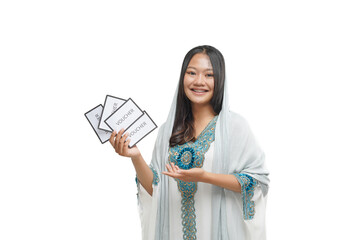 An Asian woman wearing a hijab and smiling carries a shopping voucher to celebrate Eid Fitr