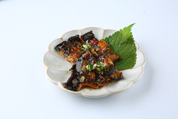 Grilled eel is on a round plate on a white background.