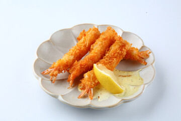 There is fried shrimp on a round plate on a white background.