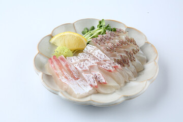 There is sashimi on a round plate on a white background.