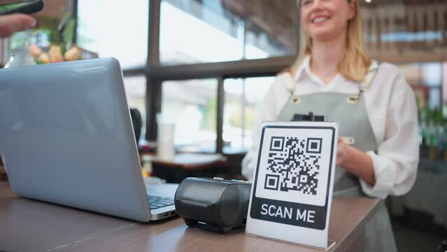 Close up of customer's hand scanning QR code to pay for coffee in cafe