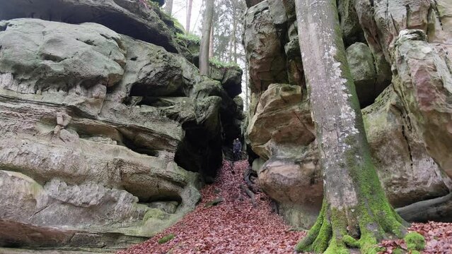 Man standing between Huge Rock Formations in Mullerthal Hiking Trail in Luxembourg - Camera on front