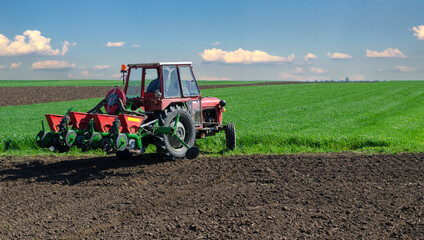 Obraz premium Farmer with tractor sowing on agricultural fields on a sunny spring day 
