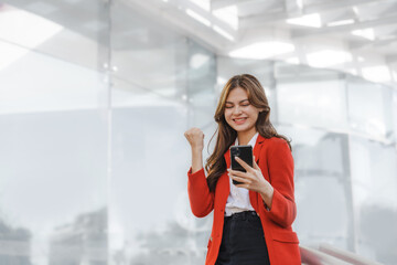 Using mobile, call phone, Smiling young Asia business woman leader entrepreneur in red color suit working outdoor urban street walk.