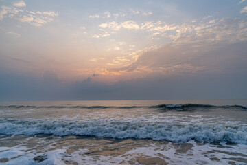 Amazing peaceful sunset slowly falls behind the clouds, With relaxing sound of calm waves of Hua Hin beach