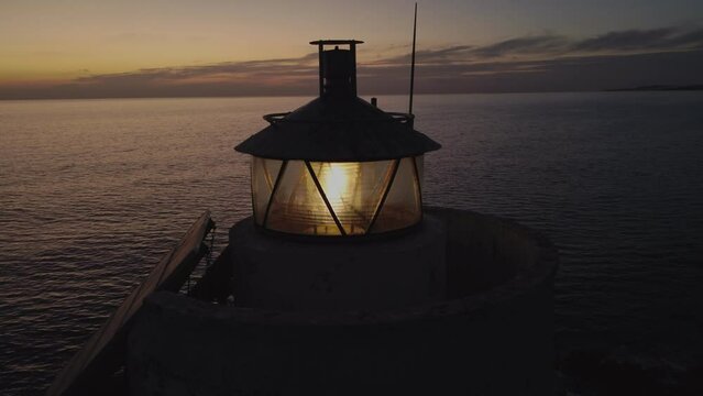 Close up of striking solitary Lighthouse illuminating sea landscape at dusk