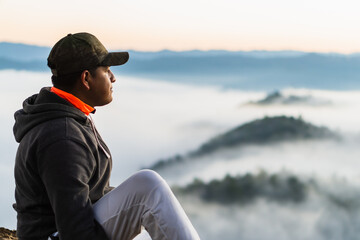 Latin and brown man looking at a landscape in a sunrise with mountains. Copy space.
