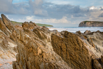 Praia rochosa e uma ilha ao fundo.