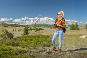 Woman traveler with an digital camera in mountains. Hiking adventure summer vacations outdoor.