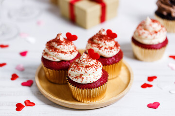 Small cupcakes with red hearts on wooden background.