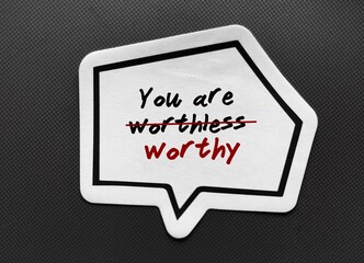 Word sticker with text YOU ARE WORTHLESS, crossed out to YOU ARE WORTHY - concept of overcome...