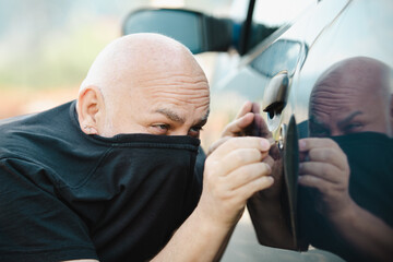 Close up car thief stealing car. Unlocked car, man trying to break into inside.