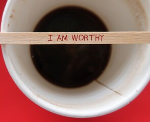 Blur coffee cup and wood stirer with handwritten text I AM WORTHY - concept of self talk...
