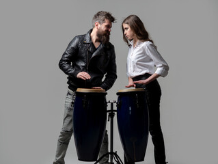 Couple hitting on conga drums isolated on gray background. Man and woman playing conga drums.