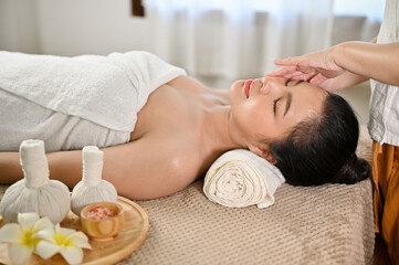 side view, Relaxed Asian woman getting facial massage, receiving special facial treatment in spa salon