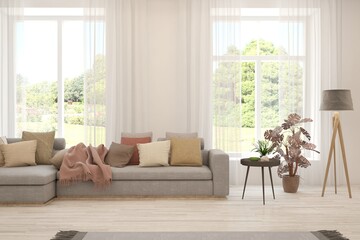 Fototapeta premium White living room with sofa and summer landscape in window. Scandinavian interior design. 3D illustration
