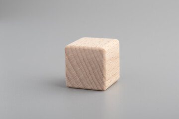 Simple empty wooden dice, one blank cubes made of wood with one central element, gray background. Copy space, logo space in the middle.