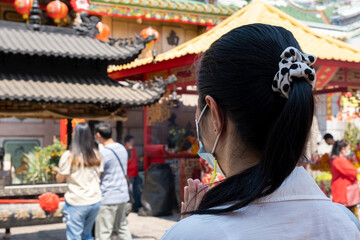 The back of an Asian woman in white shirt paying respect Buddha in Chinese temple