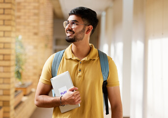 University student, college and indian man with a tablet and backpack while walking down campus corridor. Young gen z male happy about education, learning and future after studying at school building - obrazy, fototapety, plakaty