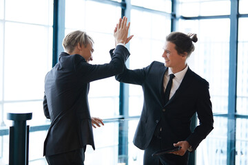 businessman giving hi five pose for success at work with friends and having fun in the office