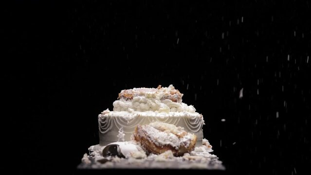 A wedding cake getting smashed by a baseball bat