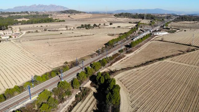 Aerial: high-speed train in Spain between Barcelona and Madrid in the catalan countryside and Montserrat mountain range in the background