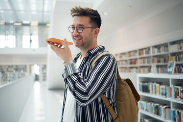 Man, phone call and speaker in library, smile and connection for communication, talking and...