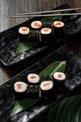 Assortment of different sushi rolls served on black plate