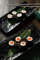 Assortment of different sushi rolls served on black plate