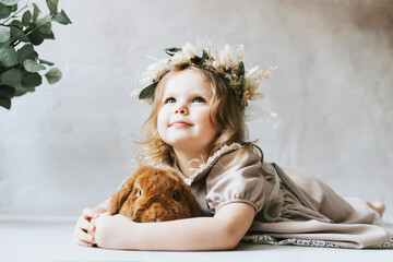 little blonde girl in vintage dress near retro background and vase with green branches eucalyptus...
