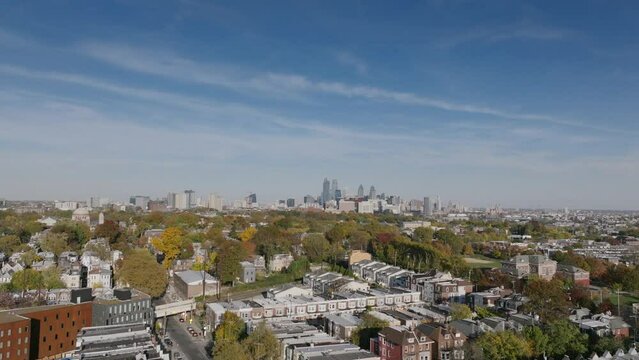 Aerial footage over the neighborhoods in West Philadelphia moving over the autumnal colored trees with downtown in the background.