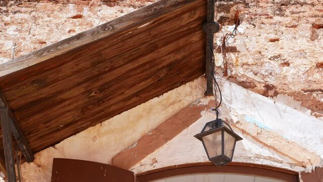 Lantern under a wooden roof swaying in the wind