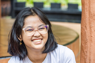 Closed up of a young Asian girl who is smiling and wearing minus glasses