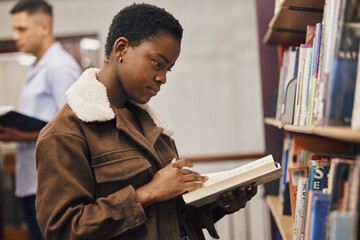 Education, book or black woman reading in library at university, college or school learning or...