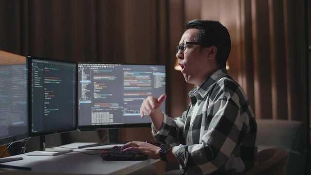 Asian Male Programmer Yawning While Creating Innovative Software Engineer Developing App, Program, Video Game On Desktop Computer At Home. Terminal With Coding Language 
