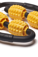 Close-up shot of a black and yellow U shape massage roller for arms and legs. The body massager is isolated on a white background. Front view.