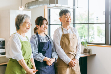 キッチンで料理する高齢者夫婦と若い日本人（家事代行・介護）  © buritora