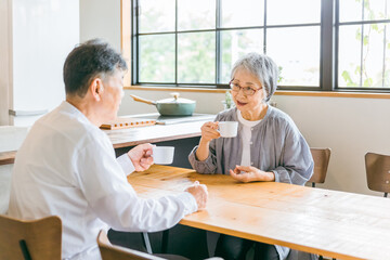 家のダイニング・カフェでお茶・コーヒーを飲むアジア人高齢者夫婦

